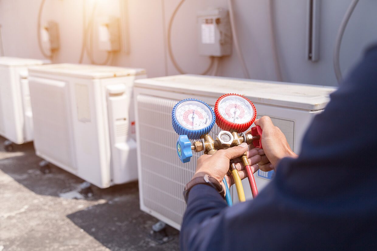 Technician checking refrigerant levels on a commercial condenser unit